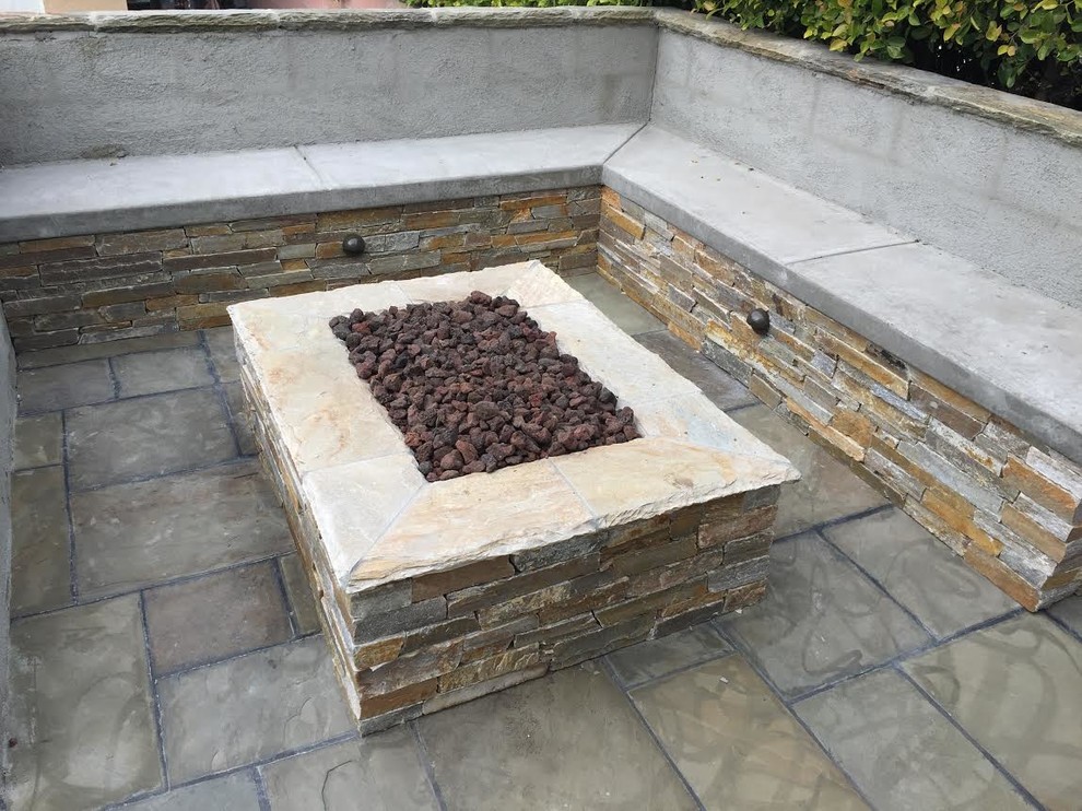 Cette image montre une terrasse arrière chalet de taille moyenne avec un foyer extérieur, des pavés en pierre naturelle et aucune couverture.