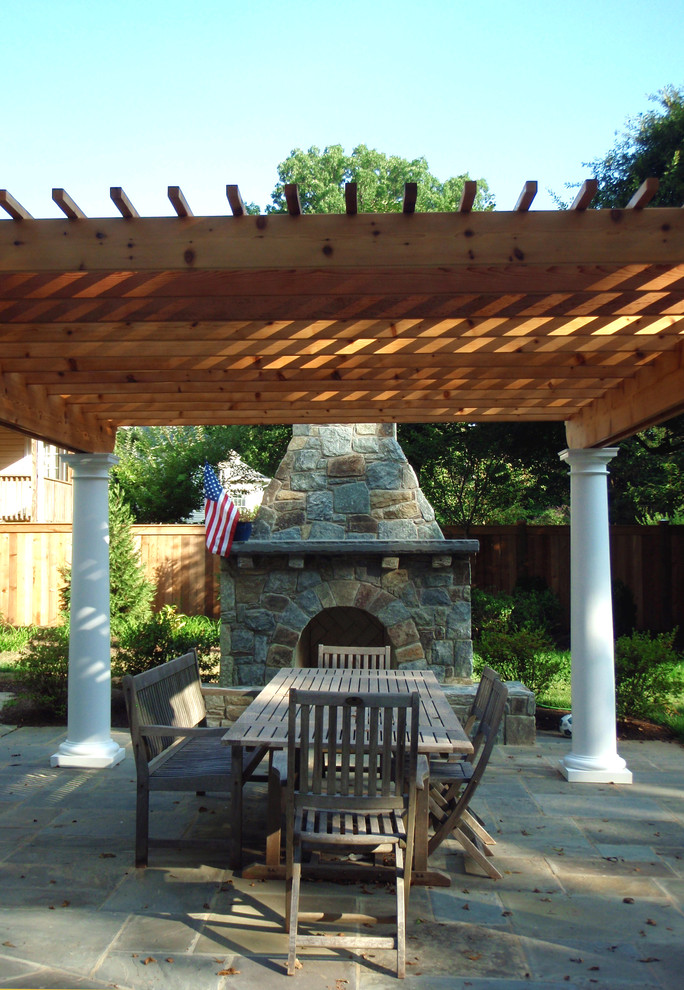 Aménagement d'une terrasse arrière contemporaine de taille moyenne avec un foyer extérieur, des pavés en pierre naturelle et une pergola.
