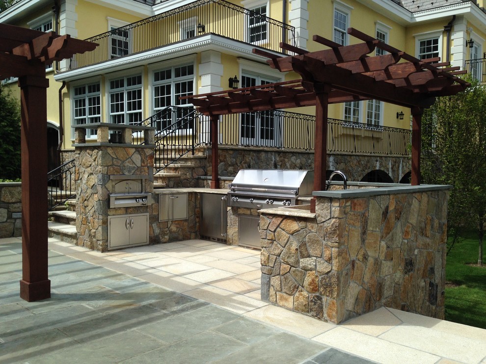 Idee per un grande patio o portico classico dietro casa con pavimentazioni in pietra naturale e una pergola