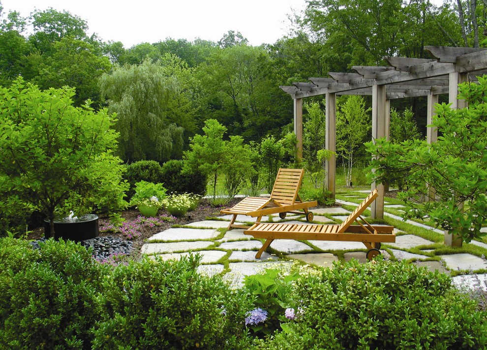 Cette image montre une terrasse arrière traditionnelle avec des pavés en pierre naturelle et une pergola.