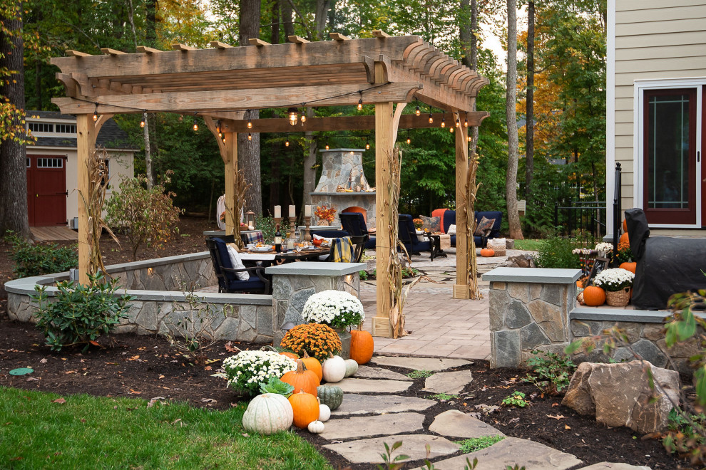 Inspiration pour une grande terrasse arrière chalet avec une cheminée, des pavés en béton et une pergola.