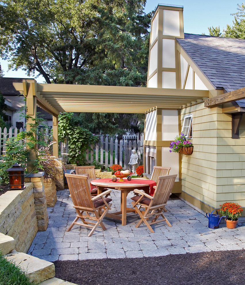 Immagine di un piccolo patio o portico chic dietro casa con un focolare, pavimentazioni in mattoni e un tetto a sbalzo