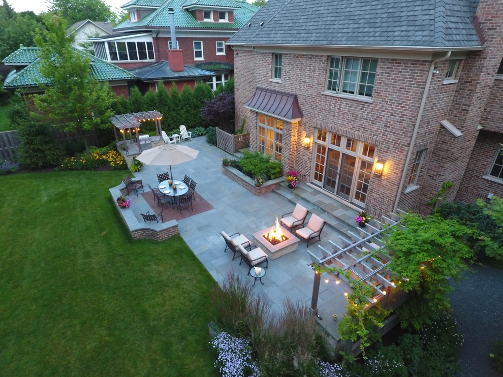 Foto di un ampio patio o portico contemporaneo dietro casa con un focolare, pavimentazioni in pietra naturale e una pergola
