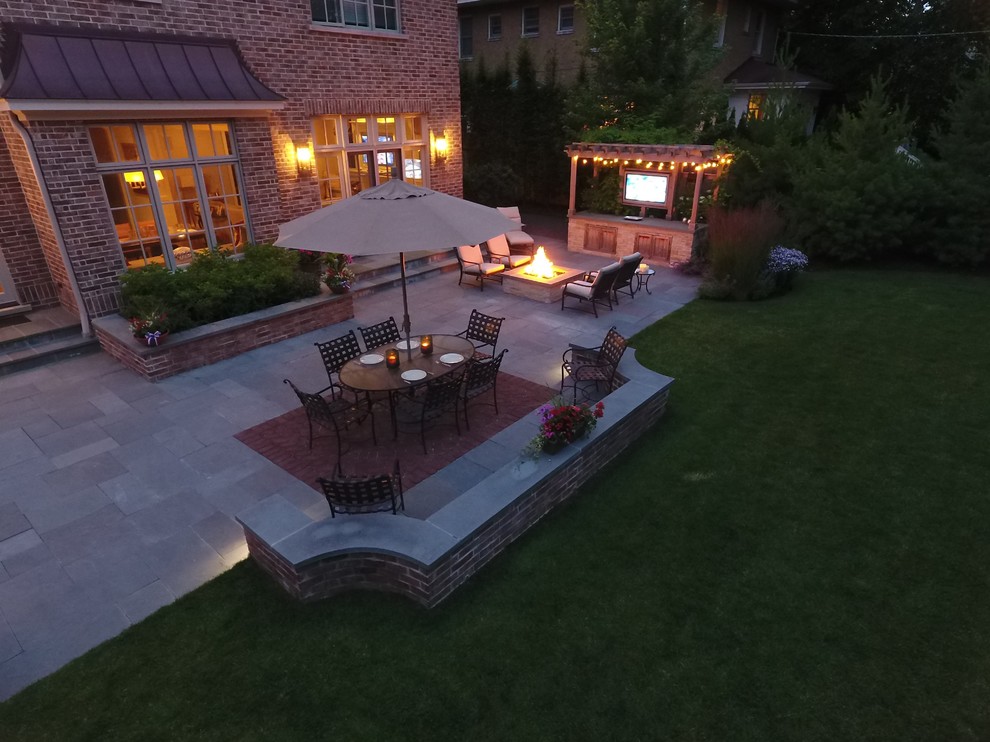 Example of a huge trendy backyard stone patio design in Chicago with a fire pit and a pergola