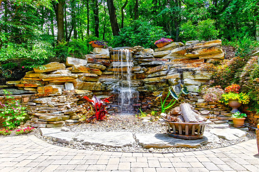 Design ideas for a large contemporary back patio in Philadelphia with a water feature, natural stone paving and no cover.