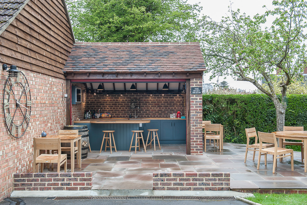 Photo of a classic back patio in Kent with natural stone paving, no cover and a bar area.
