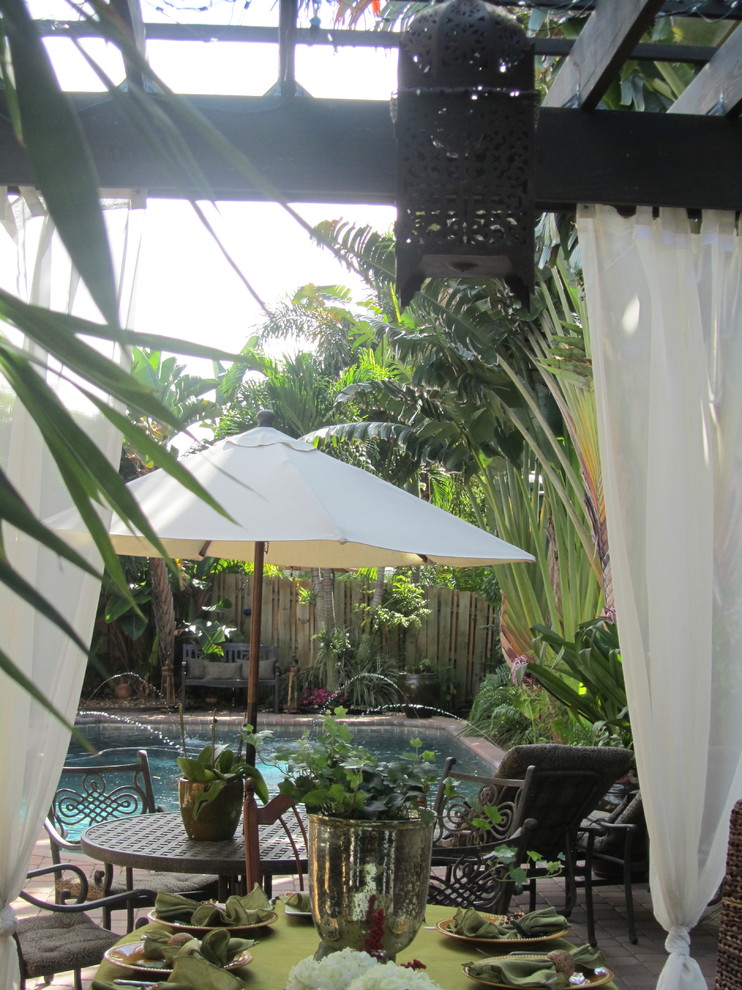 Esempio di un patio o portico tropicale con una pergola e fontane
