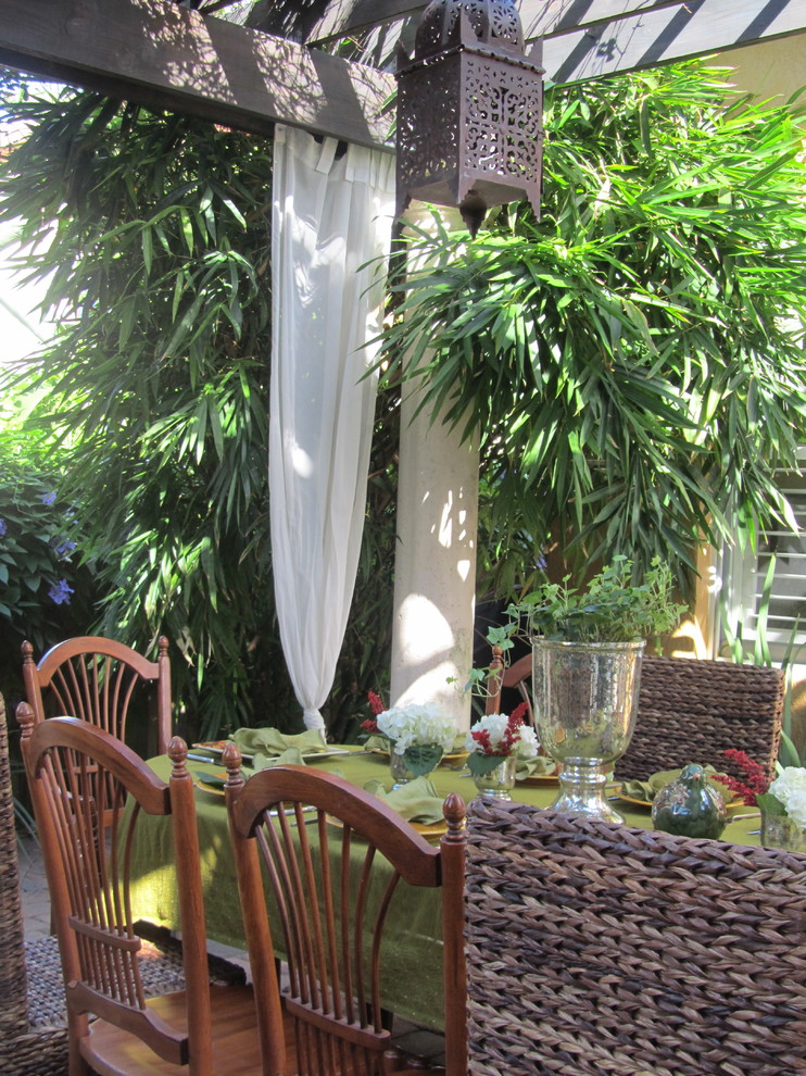 Example of an island style patio design in Miami with a pergola