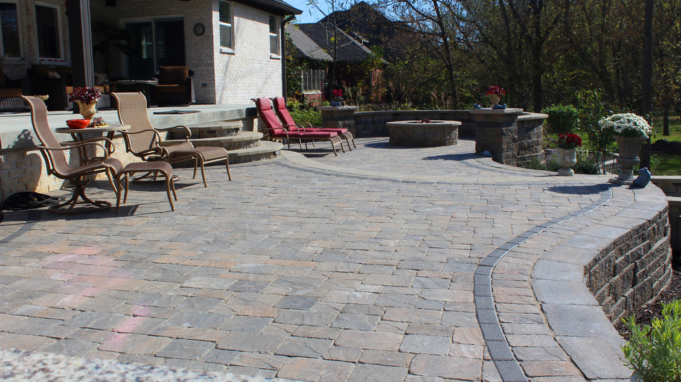 This is an example of a large traditional back patio in Indianapolis with a fire feature, concrete paving and no cover.