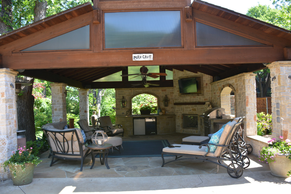 Immagine di un grande patio o portico tradizionale dietro casa con pavimentazioni in pietra naturale e un gazebo o capanno