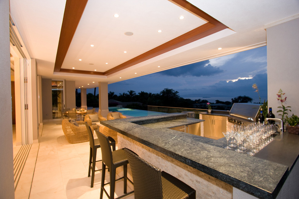 Réalisation d'une très grande terrasse arrière design avec une extension de toiture et une cuisine d'été.