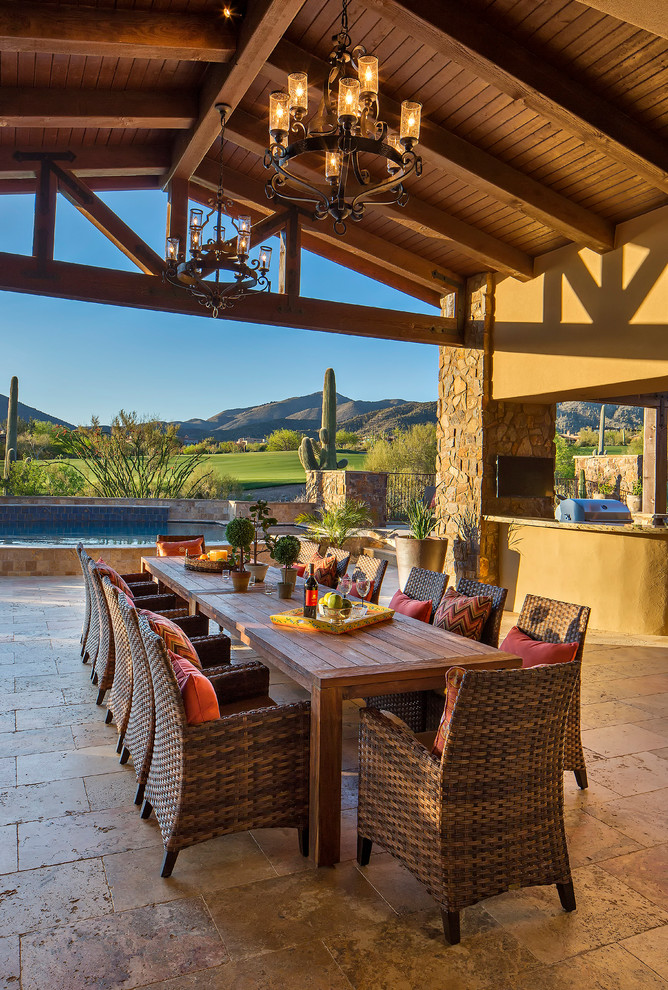 Example of a tuscan patio design in Phoenix with a roof extension