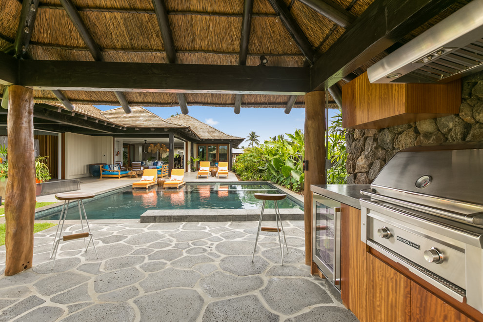 Foto på en stor tropisk uteplats på baksidan av huset, med naturstensplattor, utekök och ett lusthus