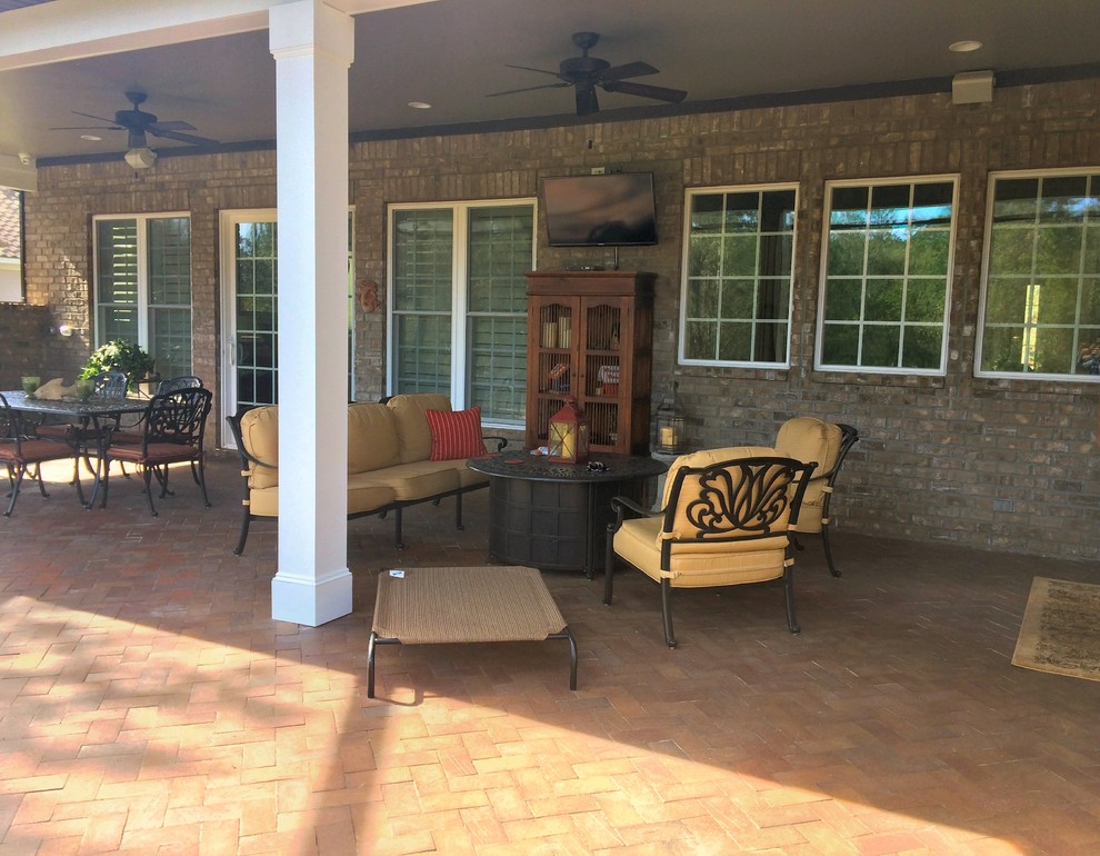 This is an example of an expansive classic back patio in Jacksonville with a fire feature, brick paving and a roof extension.