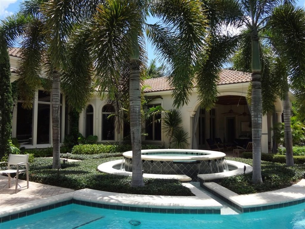 Inspiration for a large tropical backyard brick patio fountain remodel in Miami with no cover