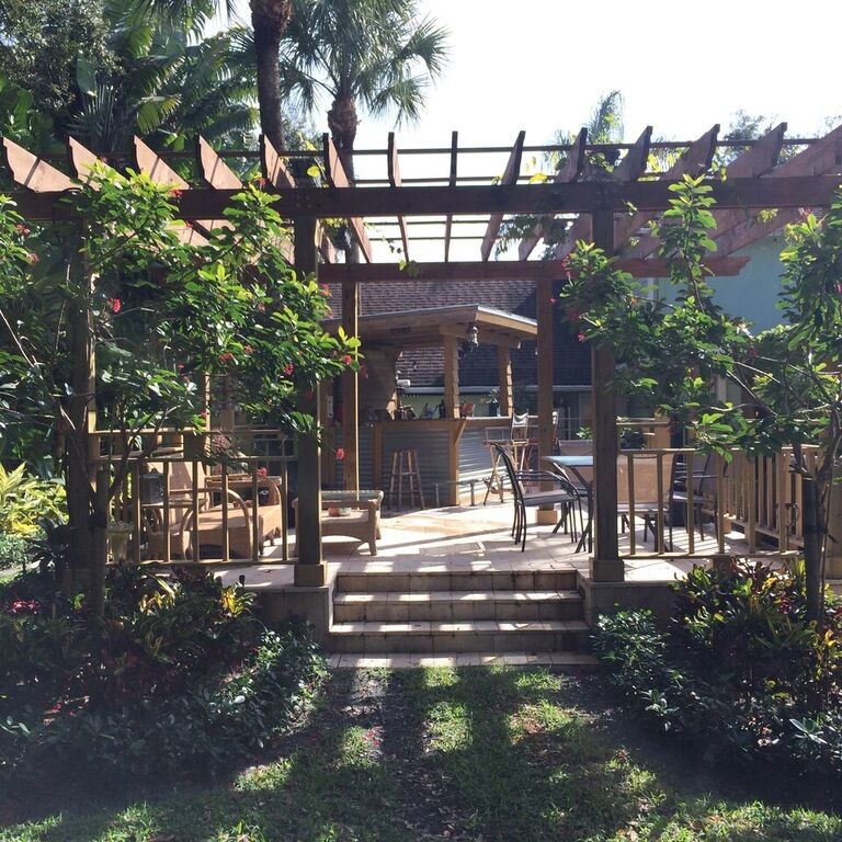 Bild på en tropisk uteplats på baksidan av huset, med naturstensplattor och en pergola