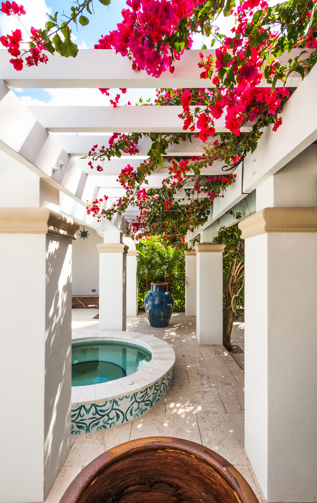 Example of an island style courtyard tile patio vertical garden design in Miami with a pergola