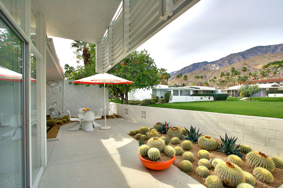 Example of a mid-century modern concrete patio design in San Francisco with a roof extension