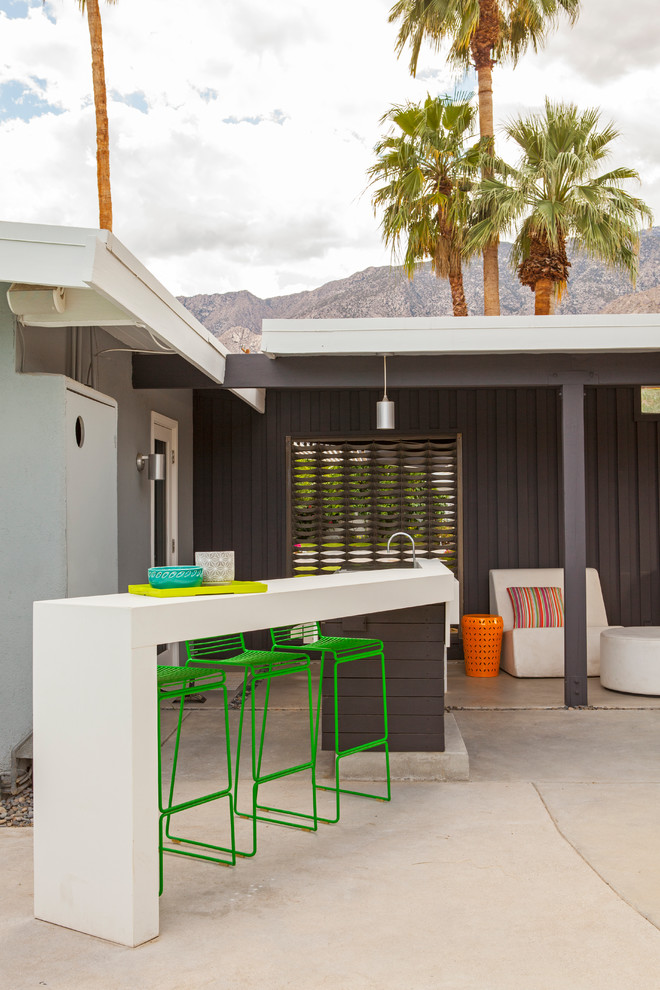 Aménagement d'une terrasse rétro avec une cuisine d'été, des pavés en béton et une extension de toiture.