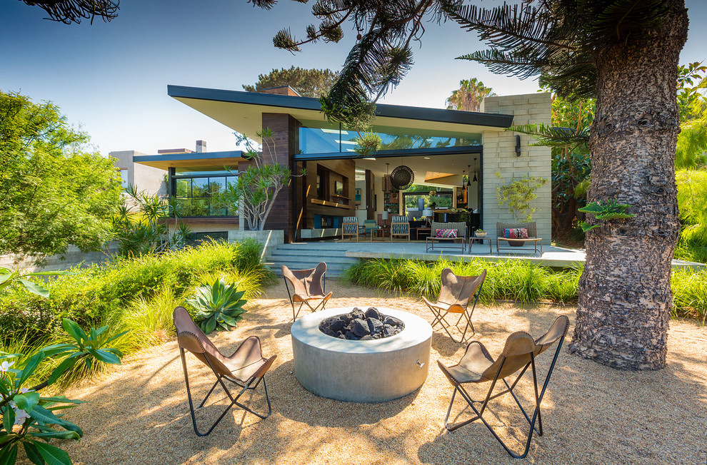 Unbedeckter Mid-Century Patio mit Kies hinter dem Haus mit Feuerstelle in San Diego