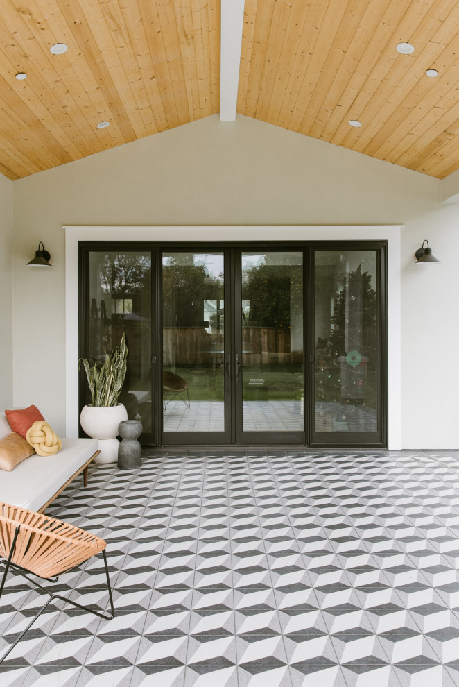 Inspiration pour une terrasse arrière minimaliste de taille moyenne avec du carrelage et une extension de toiture.