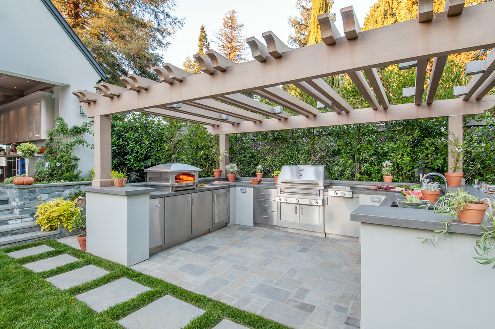 This is an example of a large back patio in San Francisco with an outdoor kitchen and a pergola.
