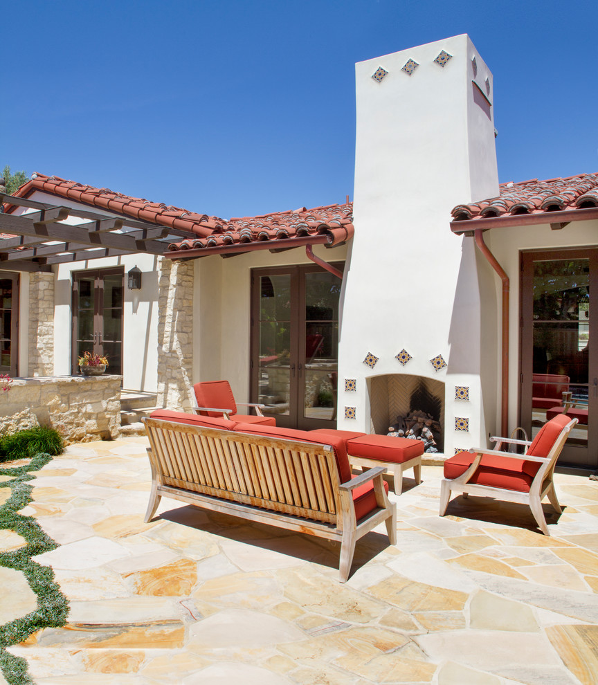 Immagine di un patio o portico mediterraneo con un focolare, pavimentazioni in pietra naturale e nessuna copertura