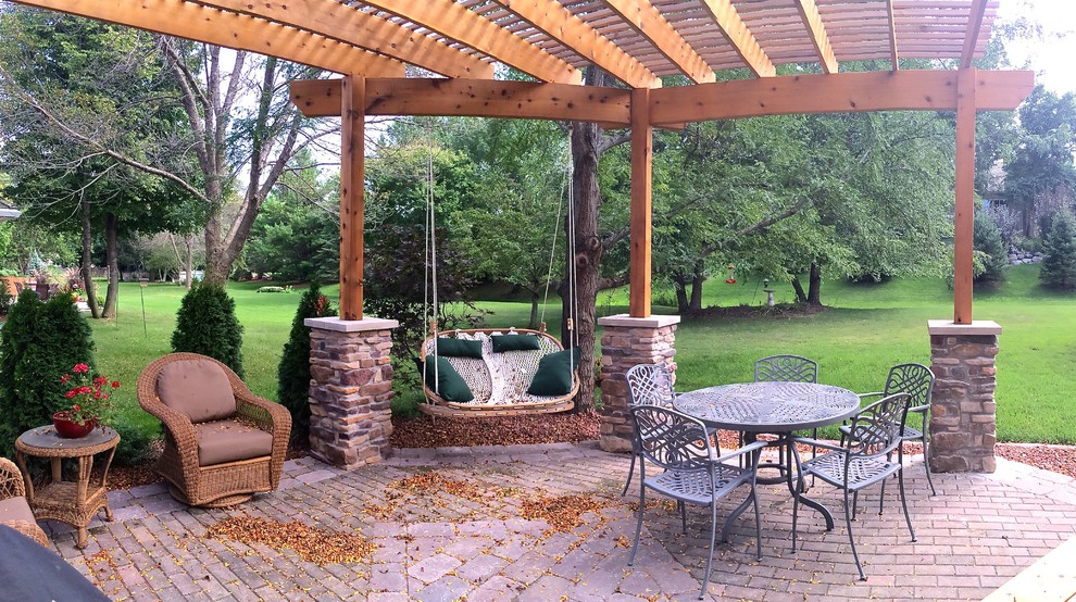 Diseño de patio tradicional de tamaño medio en patio trasero con jardín de macetas, adoquines de piedra natural y pérgola