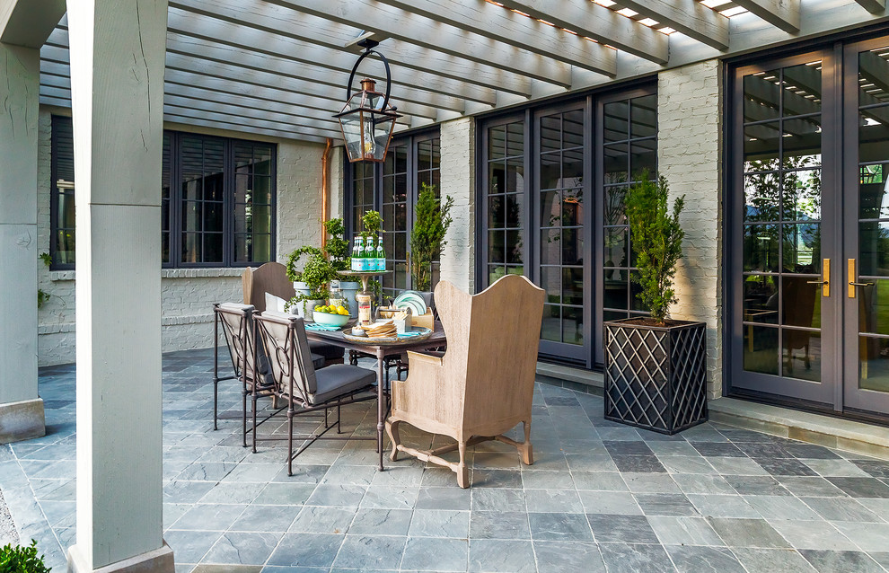 Foto de patio clásico de tamaño medio en patio trasero con jardín de macetas, adoquines de piedra natural y pérgola
