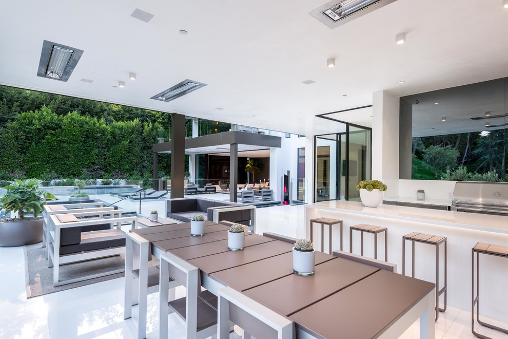 Aménagement d'une très grande terrasse arrière moderne avec une cuisine d'été, une extension de toiture et du carrelage.
