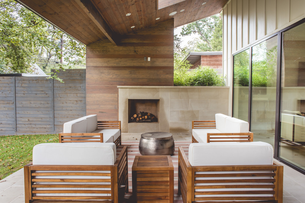 Foto di un patio o portico minimal dietro casa e di medie dimensioni con piastrelle, un tetto a sbalzo e un caminetto