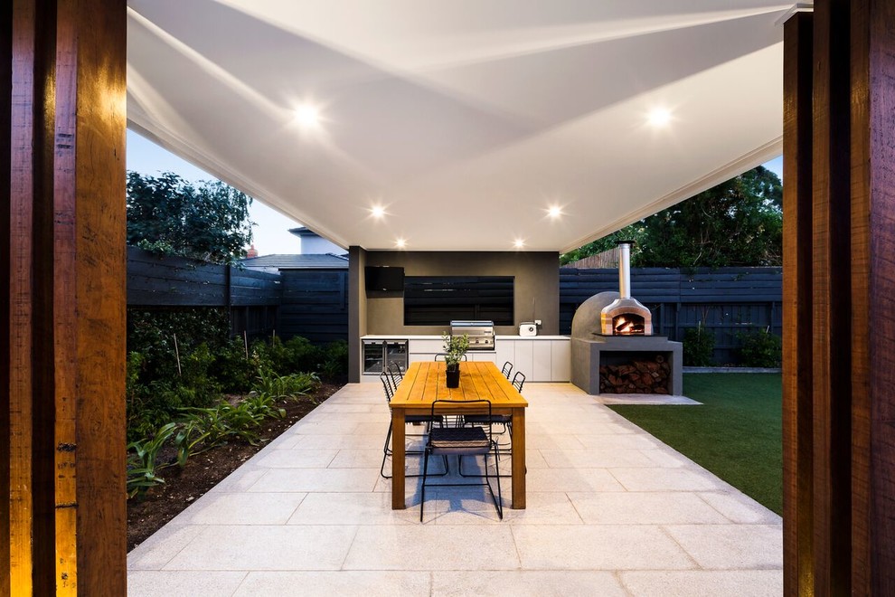 Imagen de patio actual de tamaño medio en patio trasero con cocina exterior, adoquines de piedra natural y pérgola