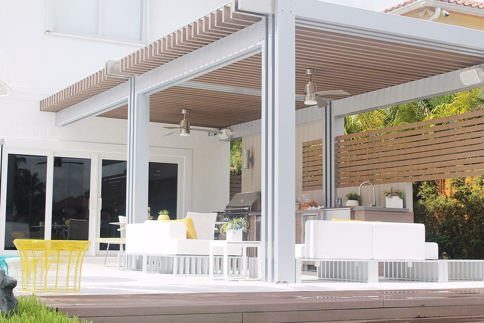 Réalisation d'une terrasse en bois arrière design avec une cuisine d'été et une pergola.
