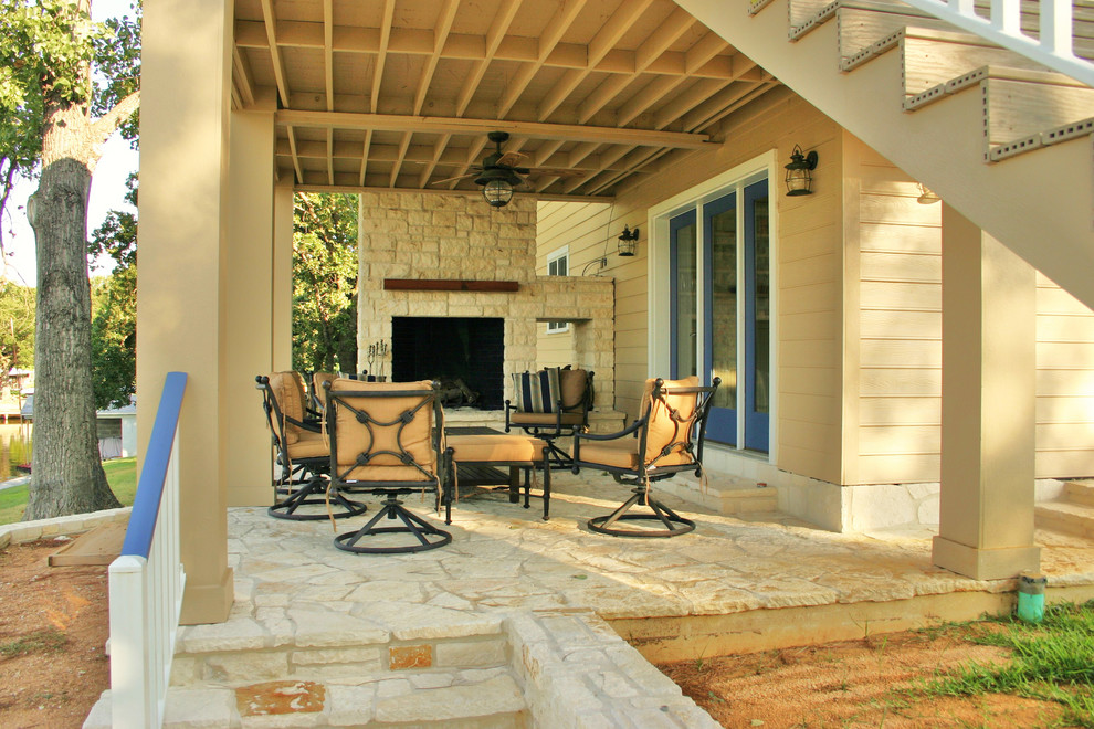 This is an example of a medium sized nautical back patio in Austin with a fire feature, natural stone paving and a roof extension.