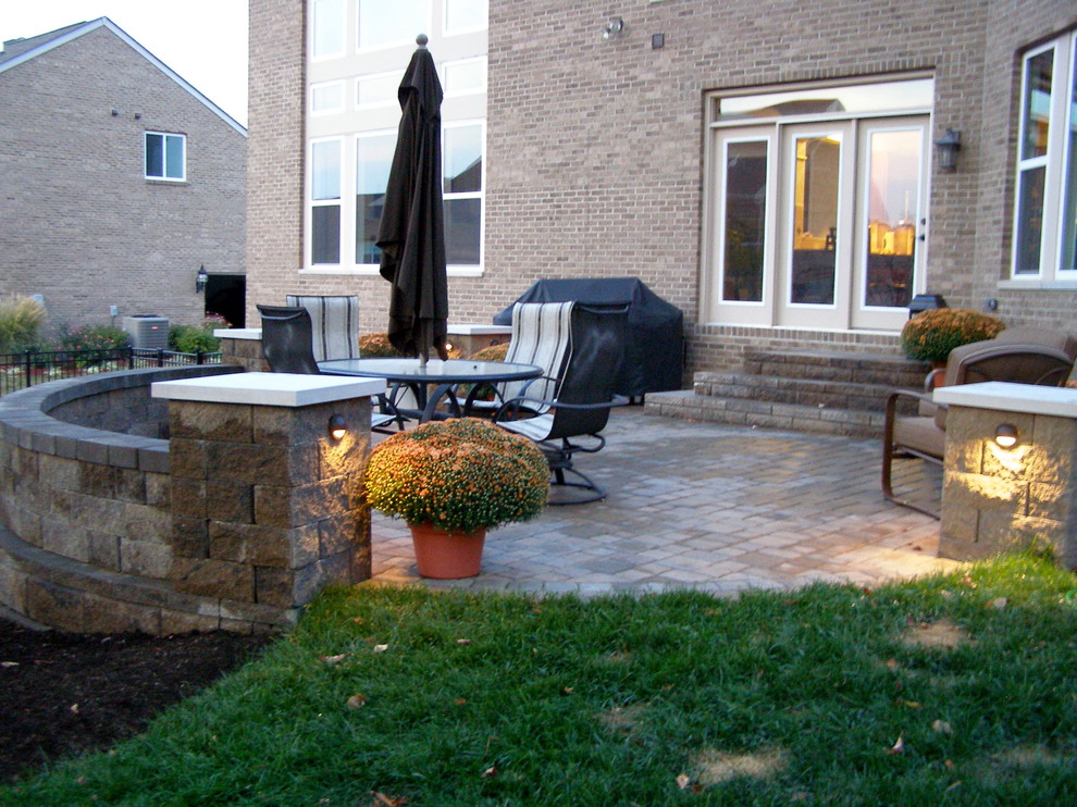 Immagine di un patio o portico chic dietro casa con un focolare e pavimentazioni in mattoni