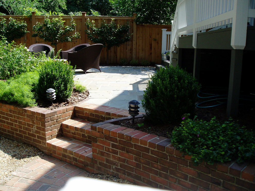 Immagine di un patio o portico american style dietro casa con un focolare, pavimentazioni in pietra naturale e nessuna copertura