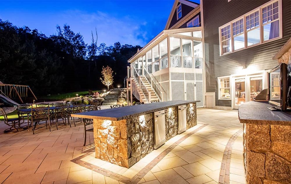 Idée de décoration pour une terrasse arrière minimaliste avec une cuisine d'été, des pavés en pierre naturelle et un auvent.