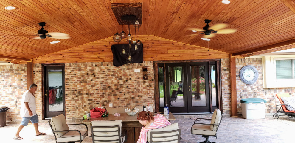 Inspiration for a large rustic back patio in Houston with tiled flooring and a roof extension.