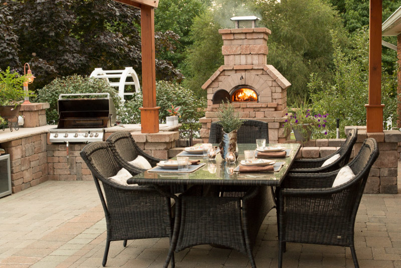 Modelo de patio clásico renovado de tamaño medio en patio trasero con cocina exterior, adoquines de ladrillo y pérgola