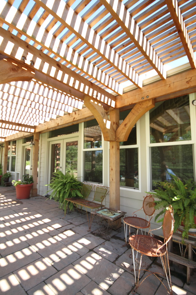 Immagine di un patio o portico country dietro casa con pavimentazioni in mattoni e una pergola
