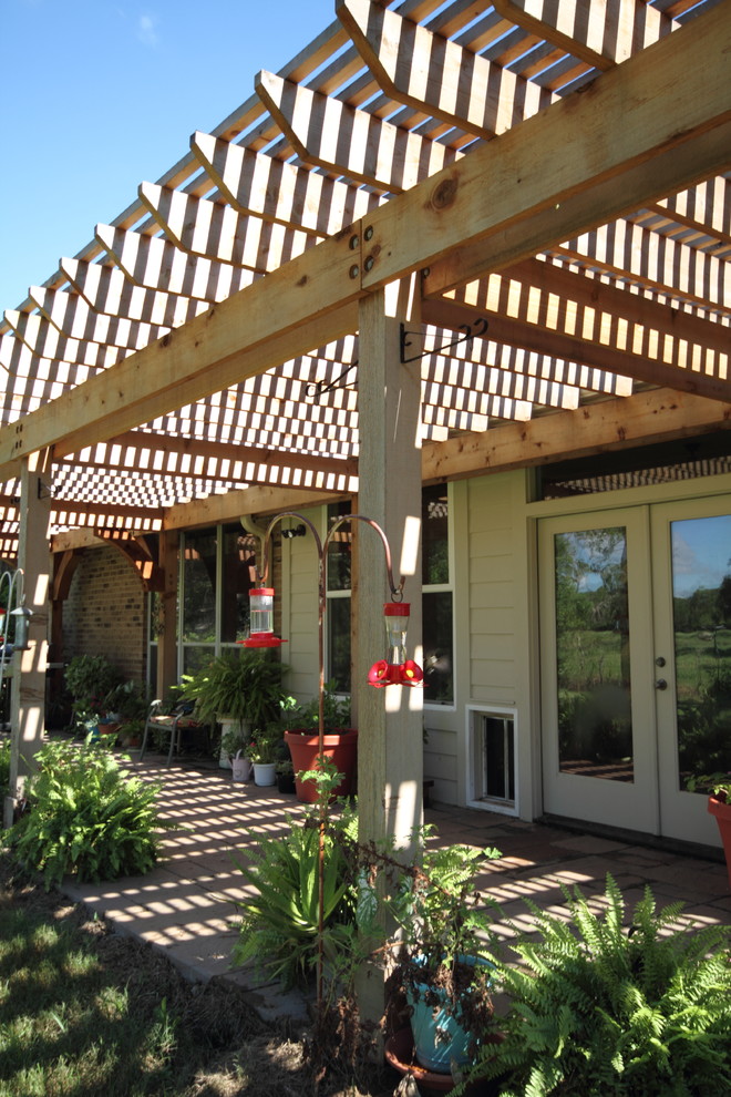 Immagine di un patio o portico country dietro casa con pavimentazioni in mattoni e una pergola