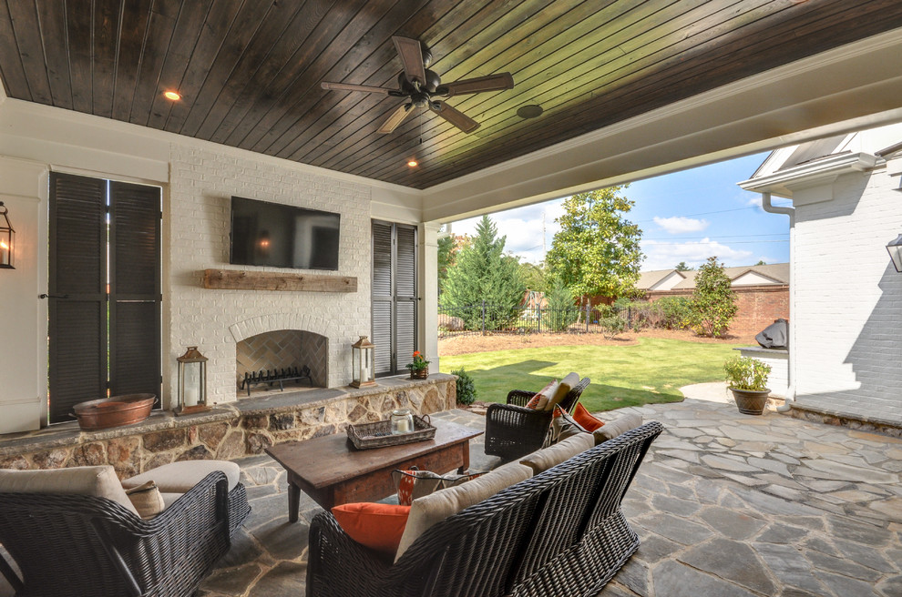 Cette image montre une terrasse arrière design avec un foyer extérieur, des pavés en pierre naturelle et une extension de toiture.