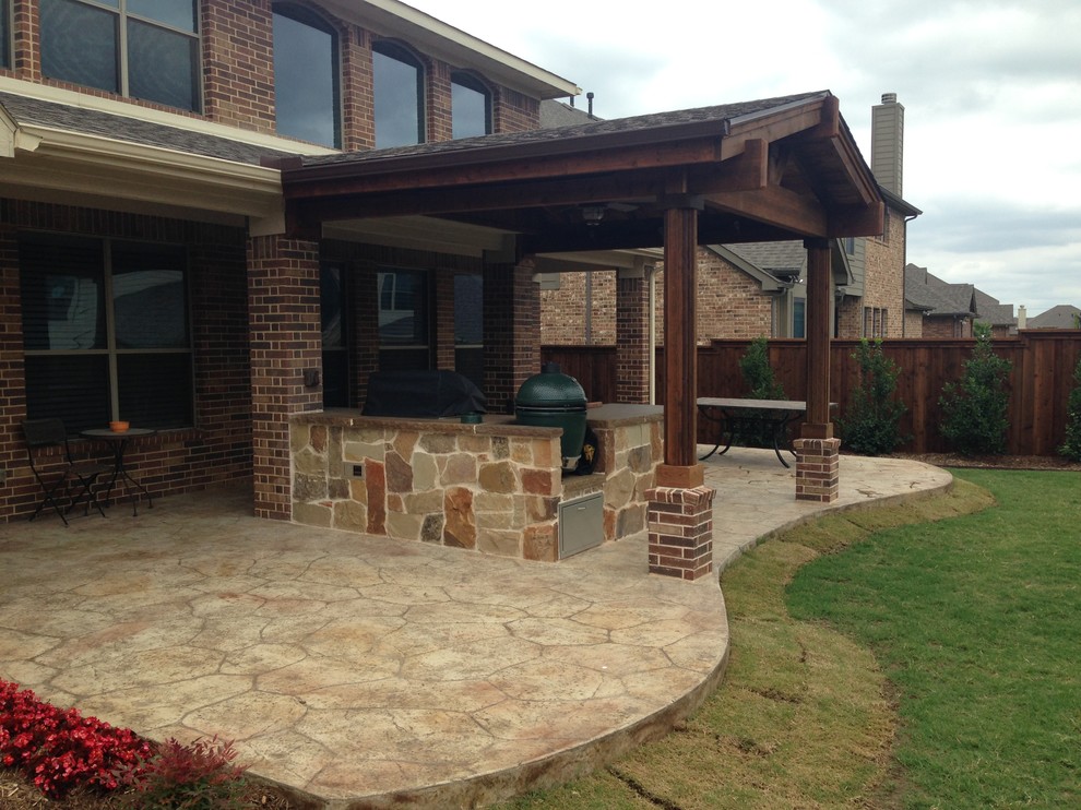 Mid-sized mountain style backyard stamped concrete patio kitchen photo in Dallas with an awning