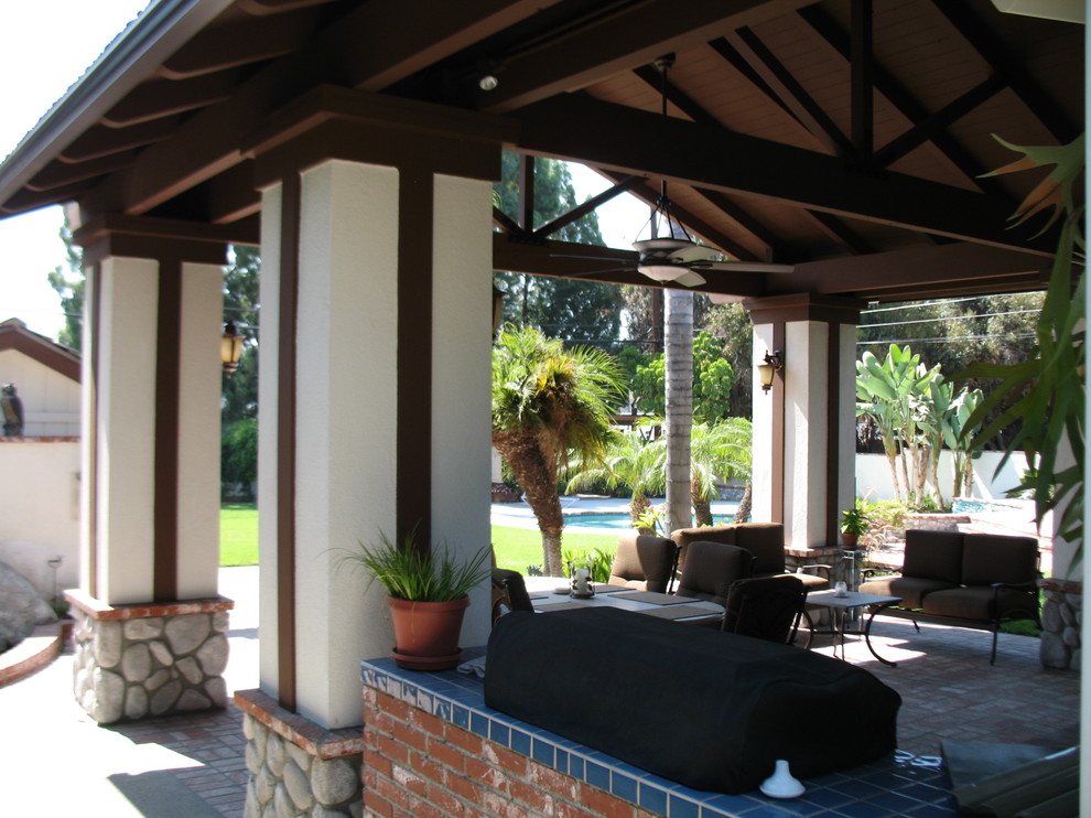 Foto di un patio o portico chic di medie dimensioni e dietro casa con pavimentazioni in mattoni e un tetto a sbalzo
