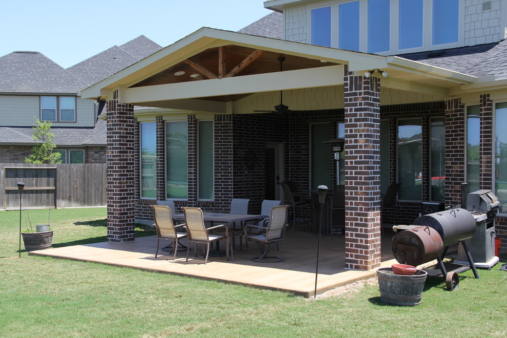 Esempio di un patio o portico tradizionale di medie dimensioni e dietro casa con cemento stampato e un tetto a sbalzo