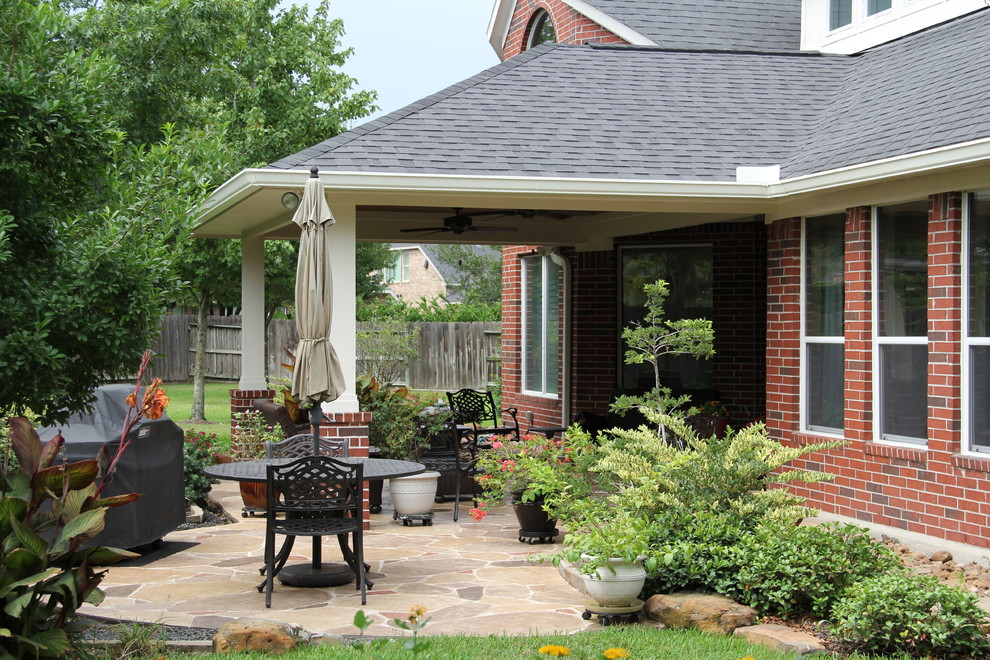 Idée de décoration pour une terrasse arrière tradition de taille moyenne avec un foyer extérieur, du béton estampé et une extension de toiture.