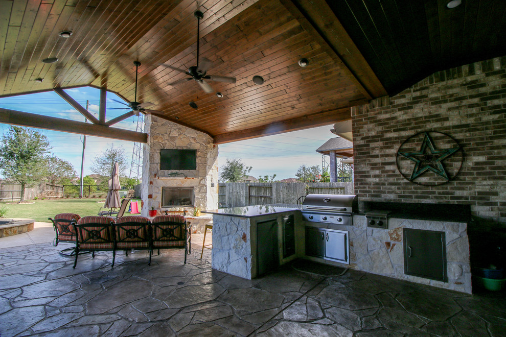 Cette photo montre une grande terrasse arrière chic avec une cuisine d'été, du béton estampé et une extension de toiture.