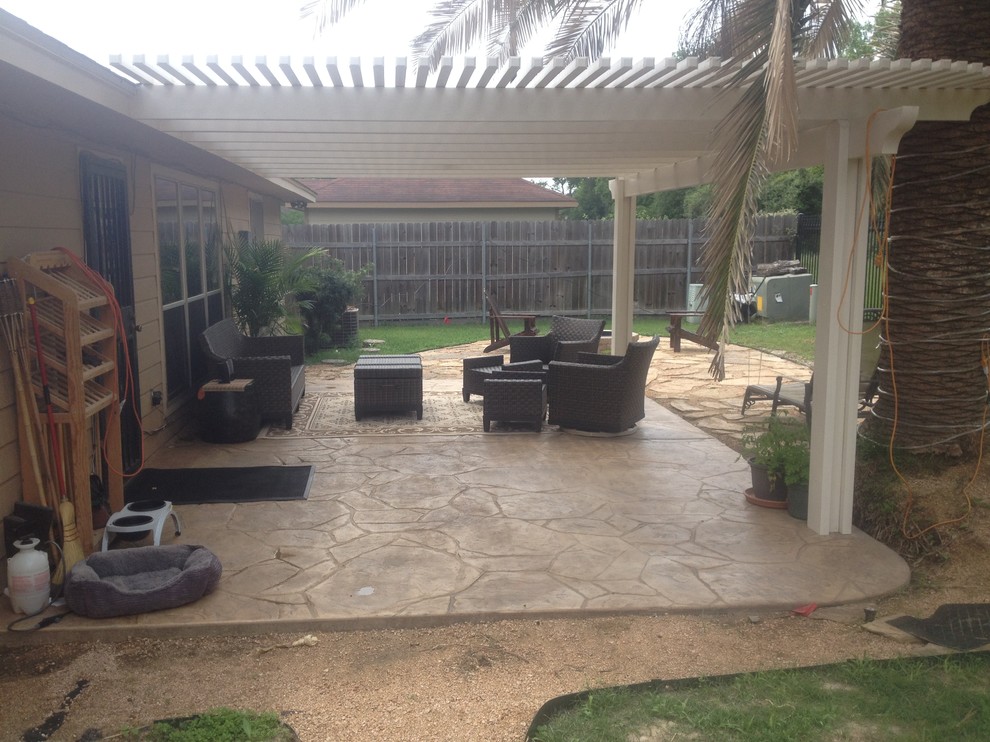 Ejemplo de patio tradicional de tamaño medio en patio trasero con suelo de hormigón estampado y pérgola