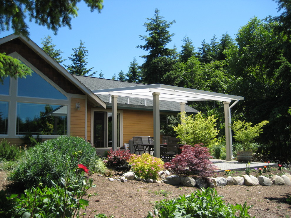 Medium sized country back patio in Seattle with concrete slabs and an awning.