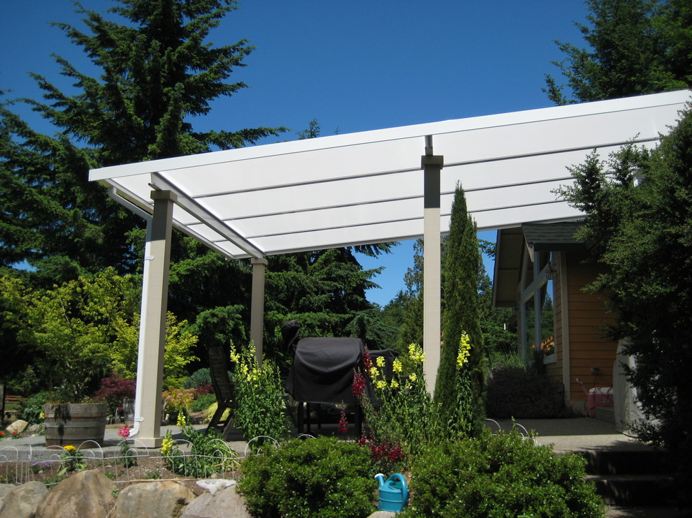 Foto di un patio o portico country di medie dimensioni e dietro casa con lastre di cemento e un parasole